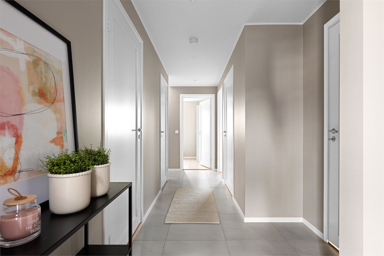 Hall med store gulvfliser, downlights i himling og plass til garderobeløsninger.