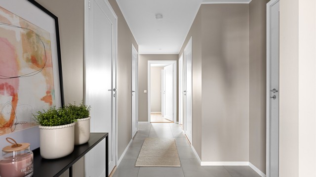 Hall med store gulvfliser, downlights i himling og plass til garderobeløsninger.
