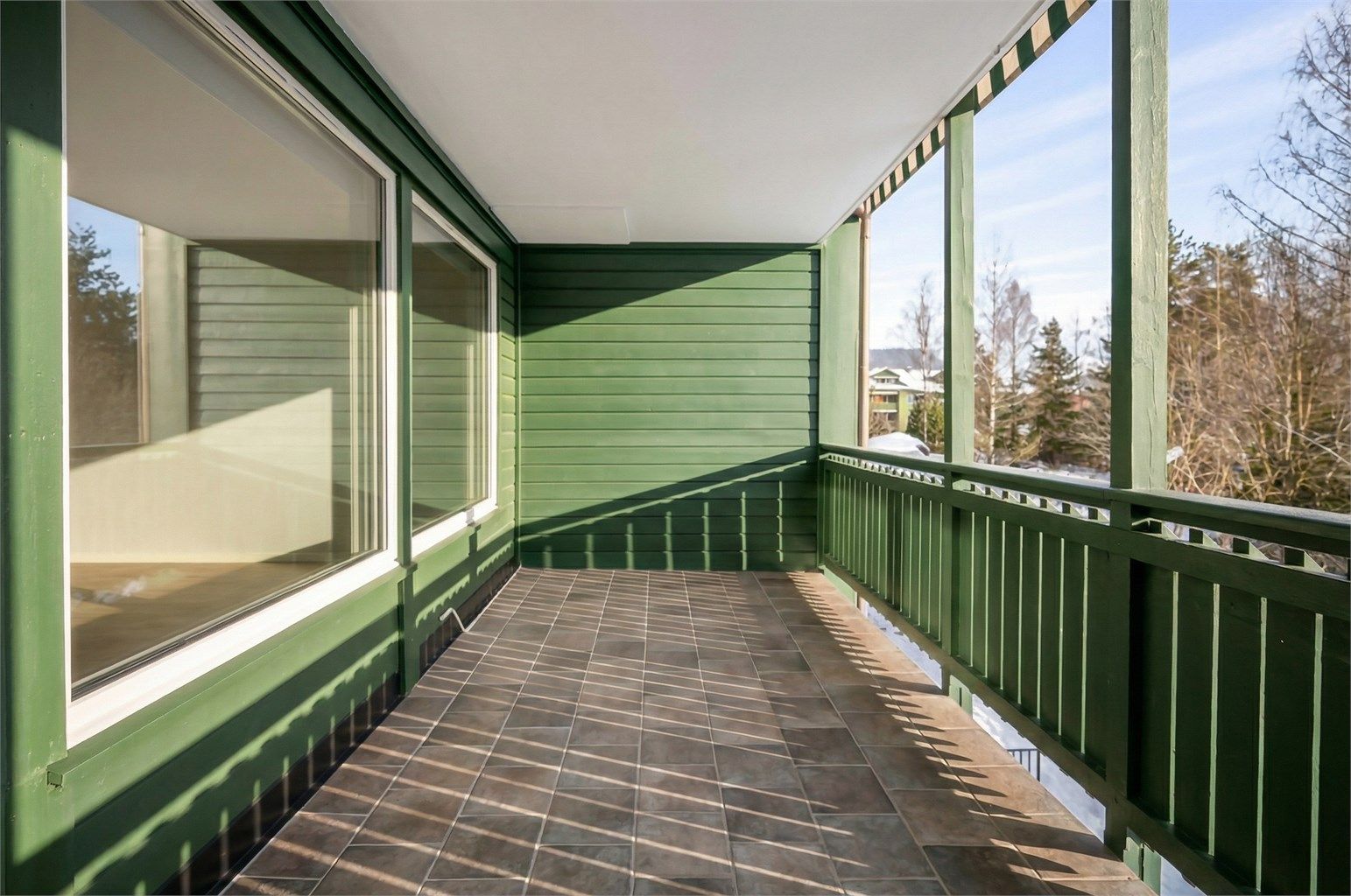 Balkongen har flislagt gulv og god plass for utemøbler.