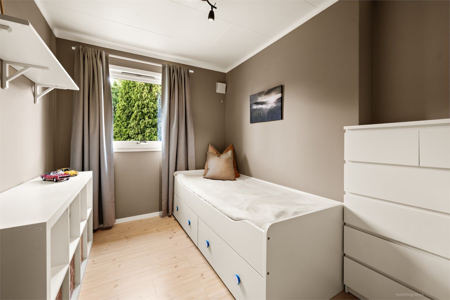Lyst og trivelig soverom med plass til seng og oppbevaring.