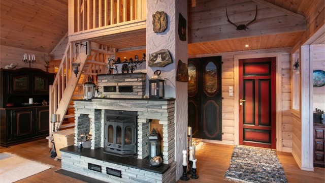 Flott murt peis med skiferstein midt i stuen som gir en lun og hyggelig atmosfære