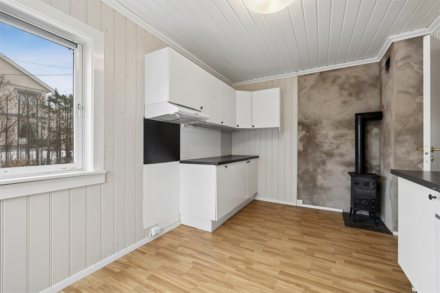 Kjøkkenet i første etasje har en eldre innredning med laminat på gulv og en vedovn i støpejern.