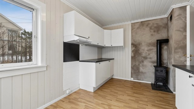 Kjøkkenet i første etasje har en eldre innredning med laminat på gulv og en vedovn i støpejern.
