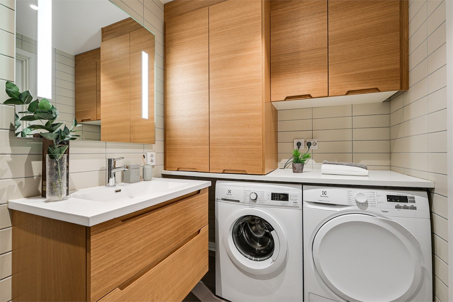Plassbygget innredning med plass til vaskemaskin og tørketrommel, samt lekker skapløsning og benkeplate som gir et eksklusivt og svært praktisk inntrykk.