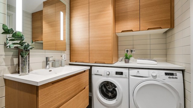 Plassbygget innredning med plass til vaskemaskin og tørketrommel, samt lekker skapløsning og benkeplate som gir et eksklusivt og svært praktisk inntrykk.