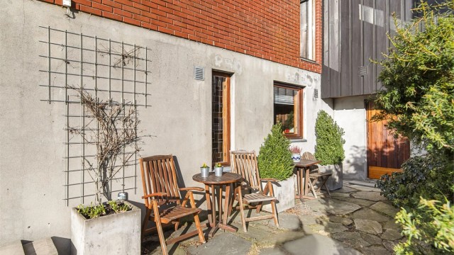 En liten, hellelagt uteplass ved siden av inngangspartiet til gangen i underetasjen ( praktisk tilgang til boder )