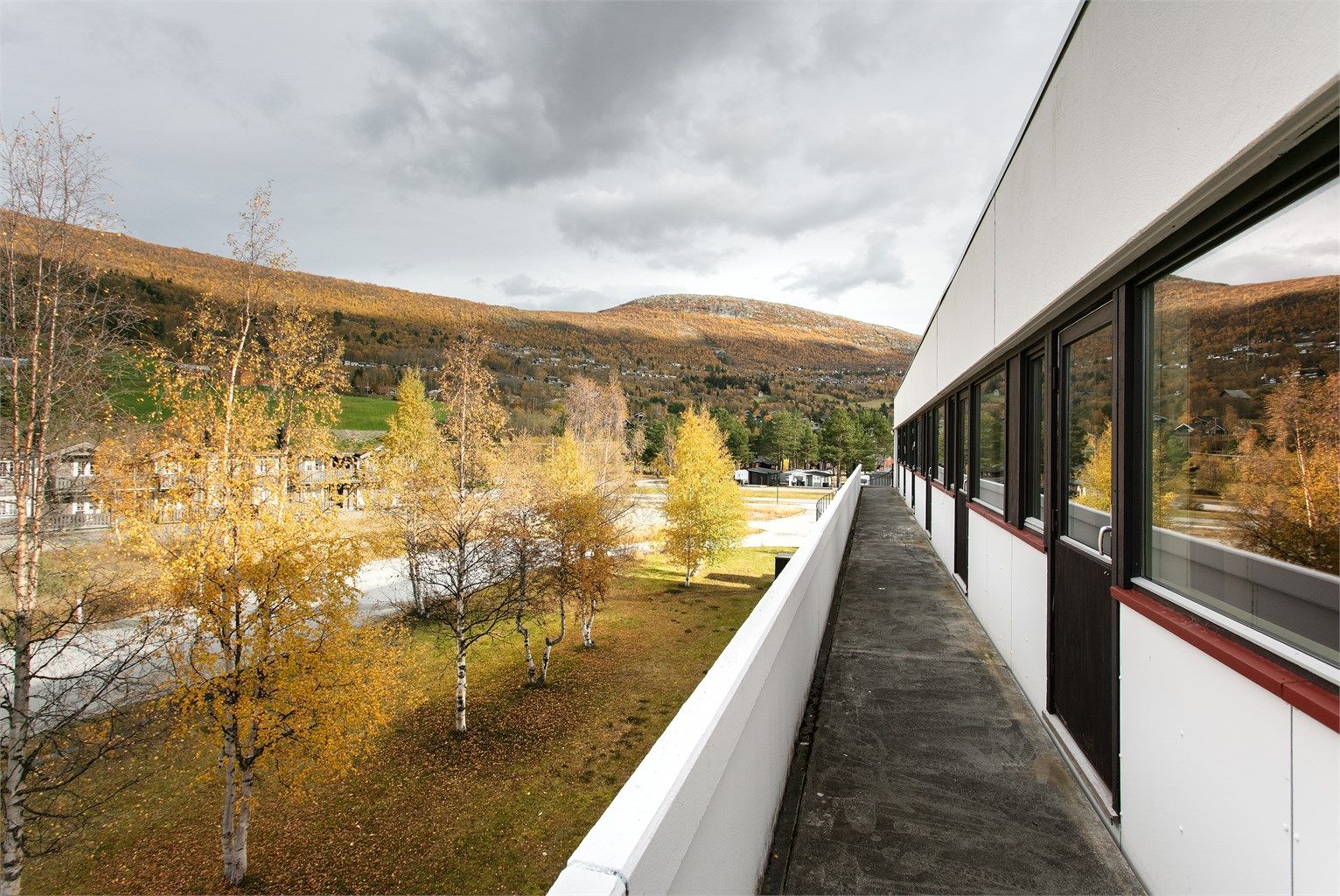 Langstrakt fellesbalkong med åpen utsikt over landskapet og fjellet.