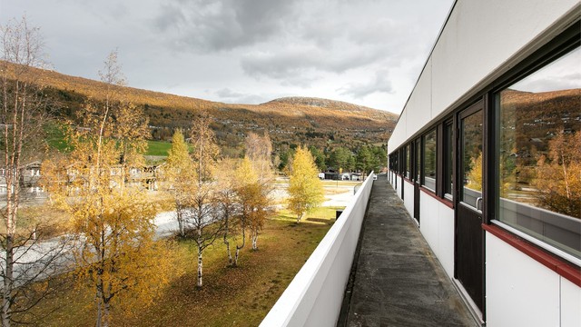 Langstrakt fellesbalkong med åpen utsikt over landskapet og fjellet.