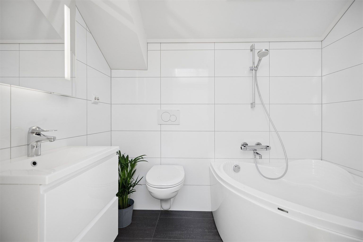 Badet i 2.etg er flislagt og har gulvvarme, vegghengt toalett, servantskap, speil med lys samt badekar. Takvinduet på badet er en strålende løsning og gjør badet lyst og innbydende uten innsyn.