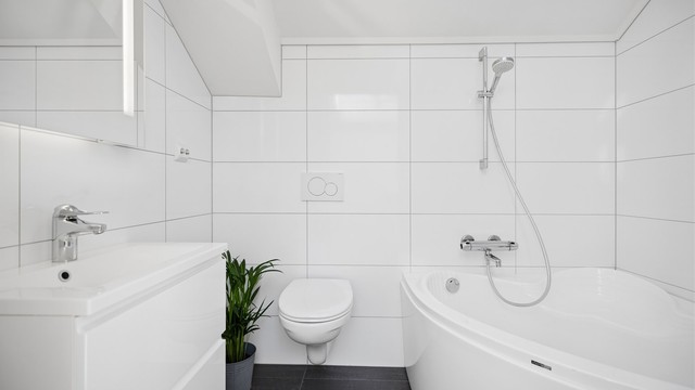 Badet i 2.etg er flislagt og har gulvvarme, vegghengt toalett, servantskap, speil med lys samt badekar. Takvinduet på badet er en strålende løsning og gjør badet lyst og innbydende uten innsyn.
