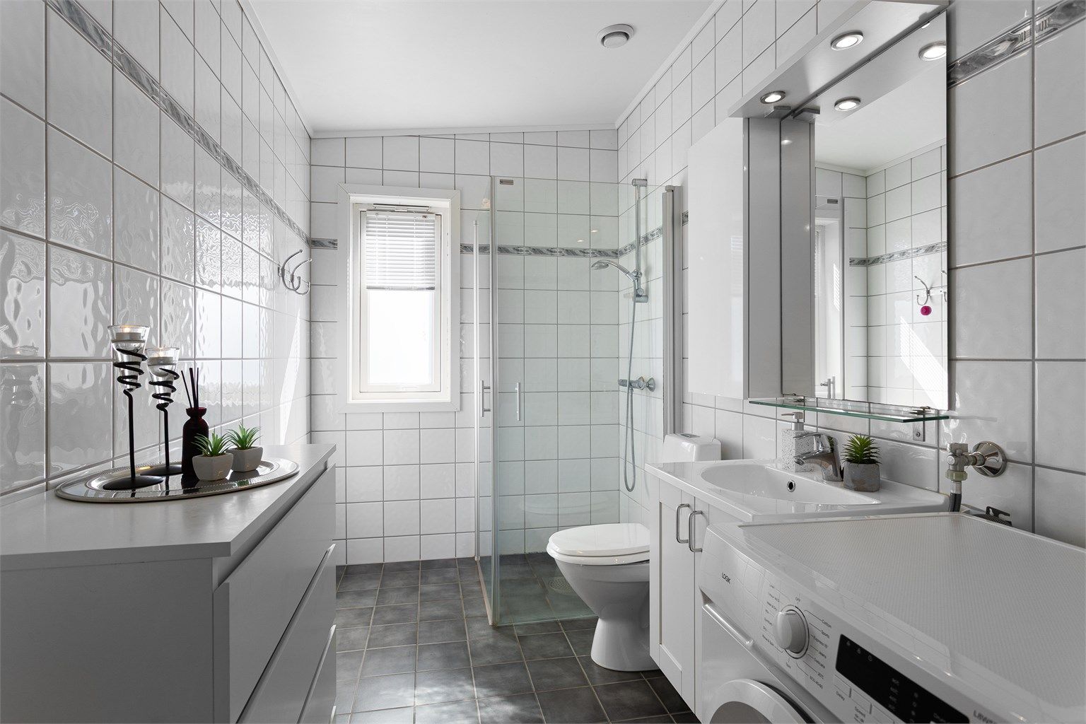 Baderomsinnredningen inkluderer en servant og speil med overlys.