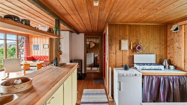 Kjøkkenet ligger i åpen løsning mot stuen og spisestuen. Innredningen er fra byggeåret, med slette fronter og benkeplater i laminat. Videre er det montert et frittstående Sunwind gasskjøleskap fra 2024 og en to-bluss gasskomfyr.