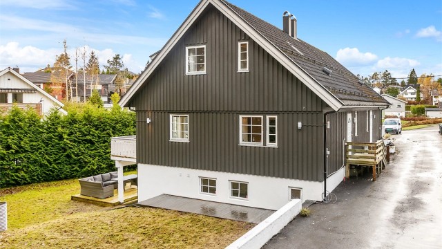 Asfaltert adkomstvei og gårdsplass samt en stor hage med hekk som gir lite innsyn.