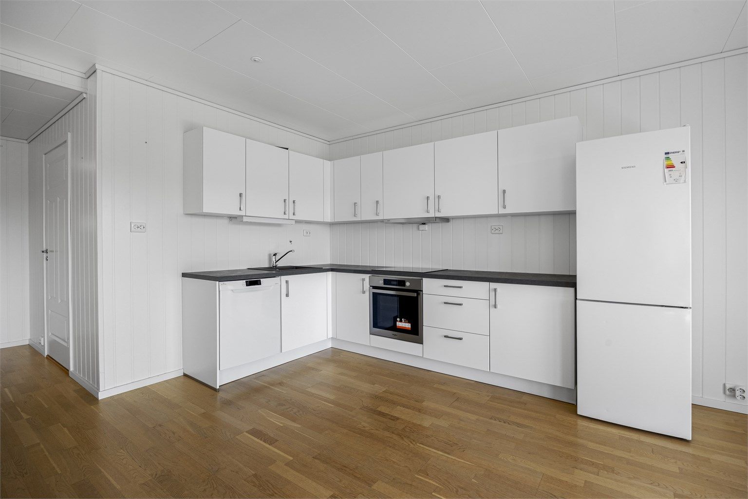 Kjøkkeninnredning fra byggeåret med glatte fronter og laminatbenkeplate.
