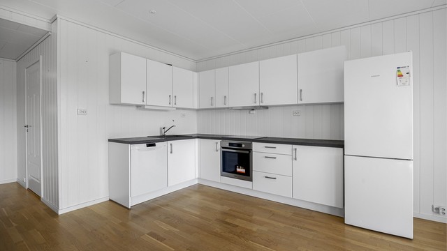 Kjøkkeninnredning fra byggeåret med glatte fronter og laminatbenkeplate.