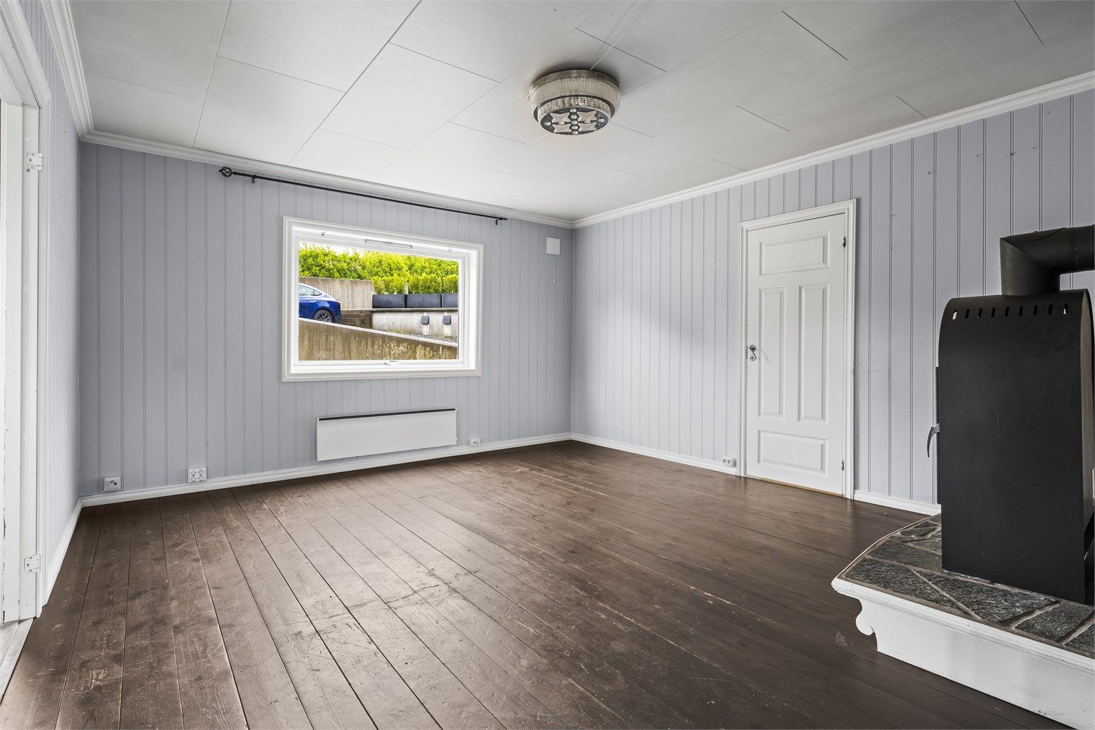 Romslig stue med vedovn og panelovn til oppvarming. Foto: A7 Media