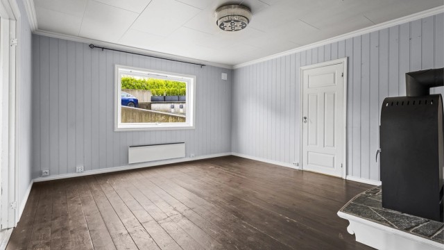 Romslig stue med vedovn og panelovn til oppvarming. Foto: A7 Media