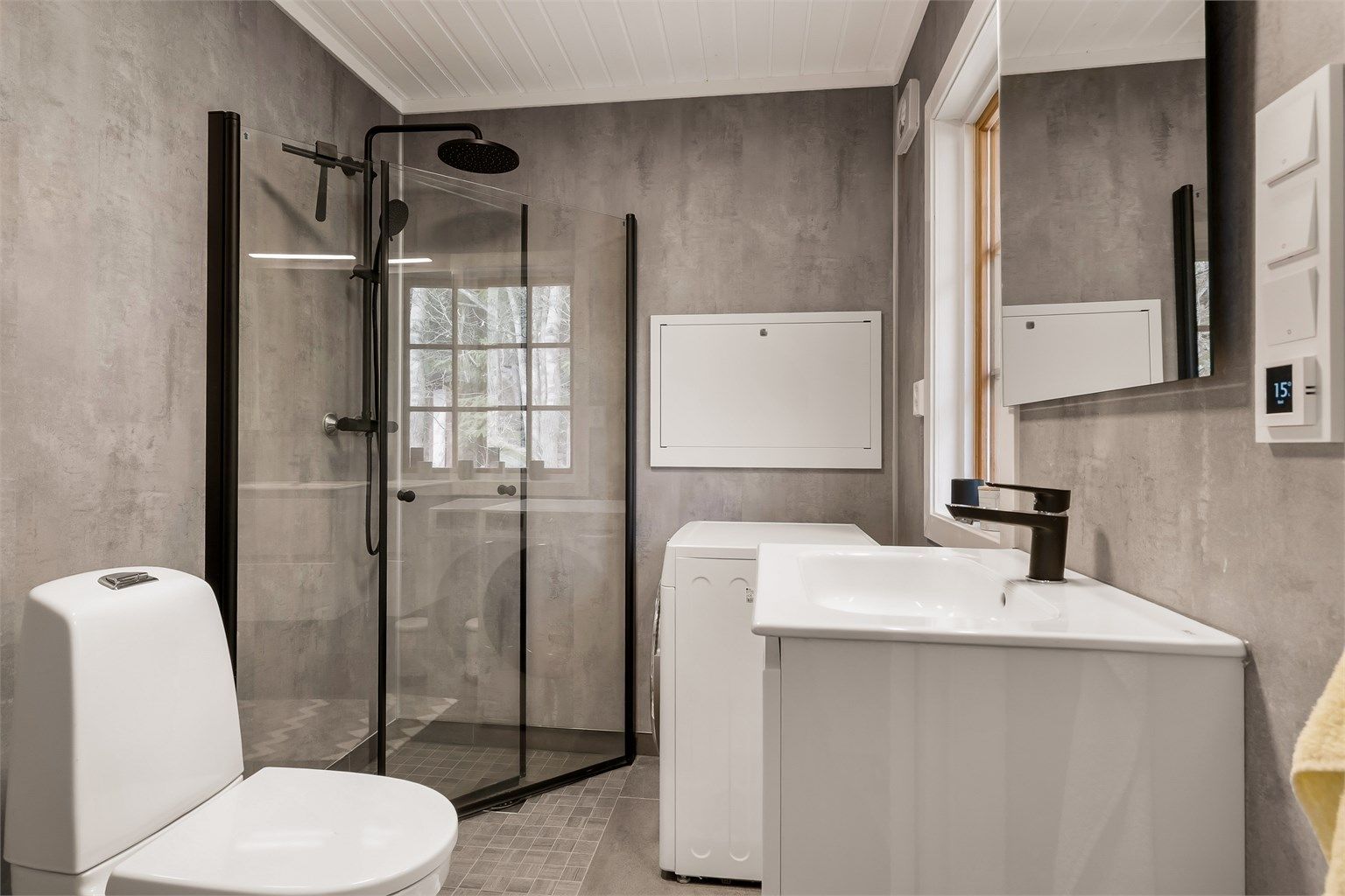 Badet har flislagt gulv og våtromsplater på veggene. Det er utstyrt med dusj, wc, servant i seksjon og vaskemaskin.