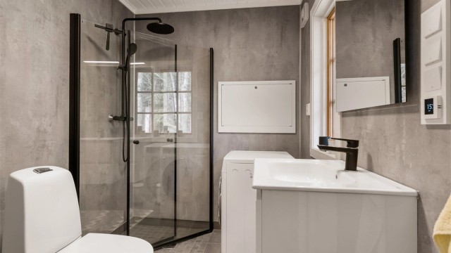 Badet har flislagt gulv og våtromsplater på veggene. Det er utstyrt med dusj, wc, servant i seksjon og vaskemaskin.