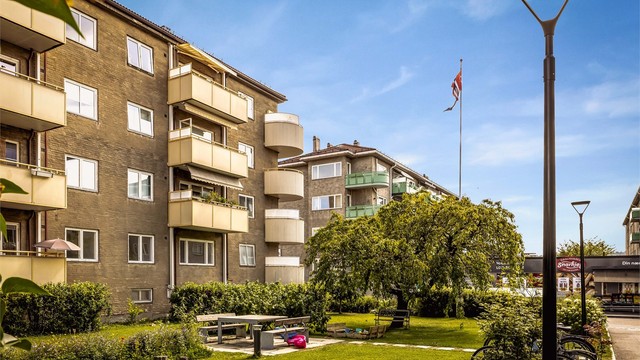 Fasade. Leiligheten vender i sin helhet mot bakgårdshagen. Fellesområdet er pent opparbeidet med gressplener, sittegrupper og lekeplass.