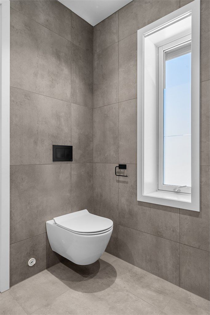 Badet har vegghengt toalett og gjennomgående, moderne materialvalg.