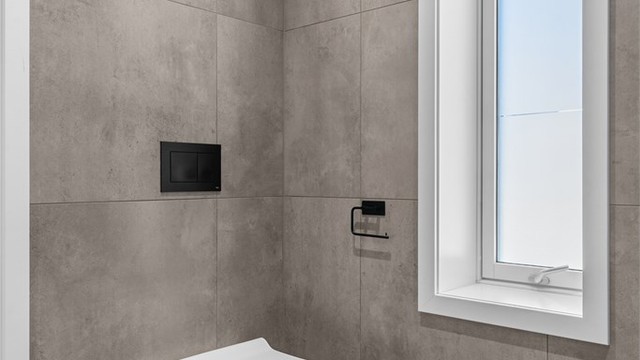 Badet har vegghengt toalett og gjennomgående, moderne materialvalg.