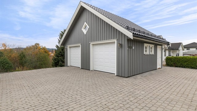 Stenlagt gårdsplass og stor dobbel garasje