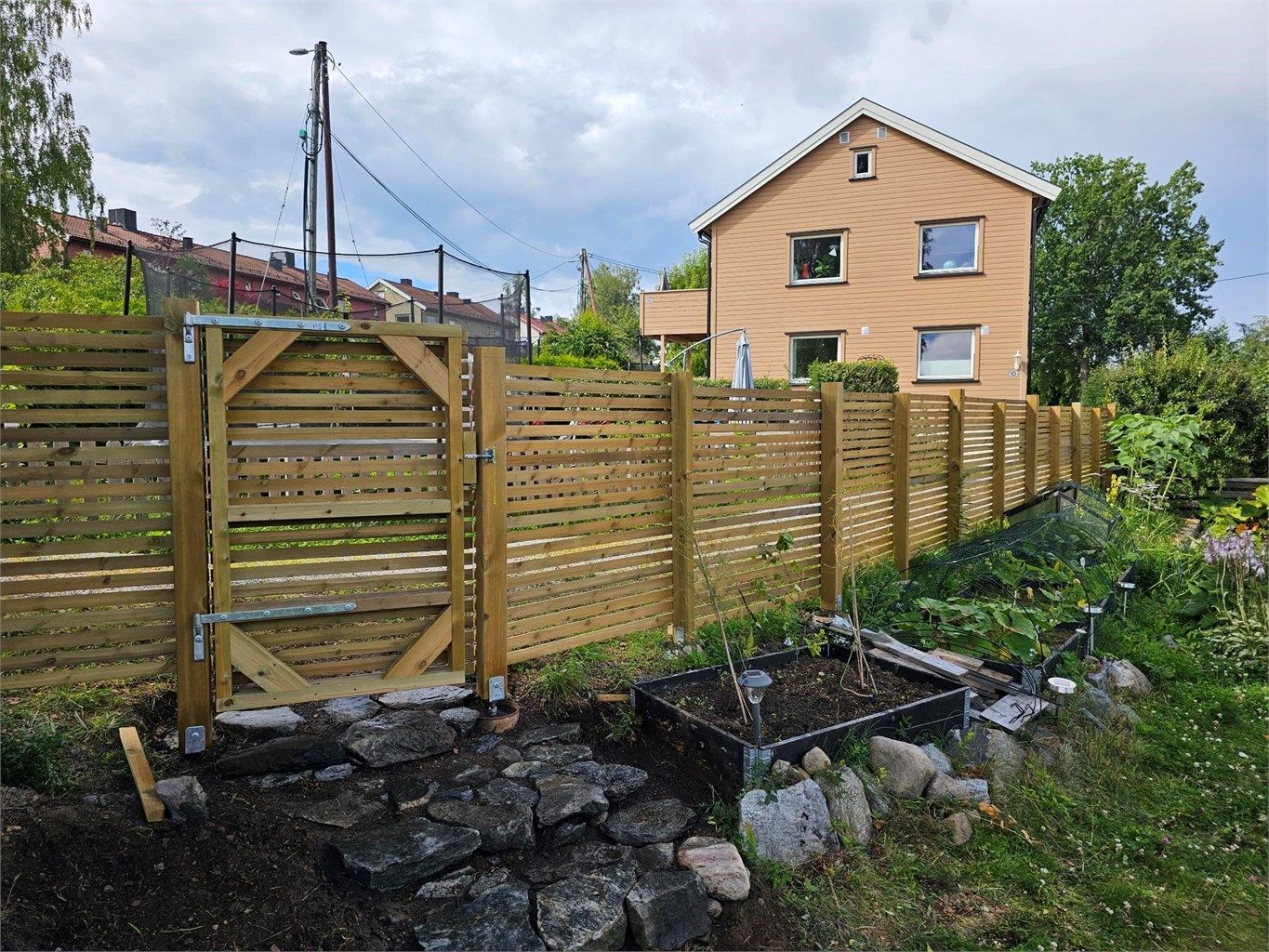 Disp. hage er pent opparbeidet med gjerde, bedd, plantekasser og busker. 