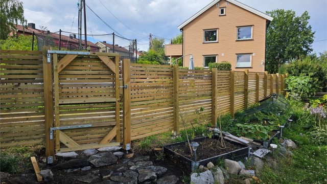 Disp. hage er pent opparbeidet med gjerde, bedd, plantekasser og busker.