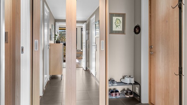 Pen entré med fliser på gulv og downlights i tak. Praktisk skyvedørsgarderobe for oppbevaring av yttertøy og sko. Gulvvarme