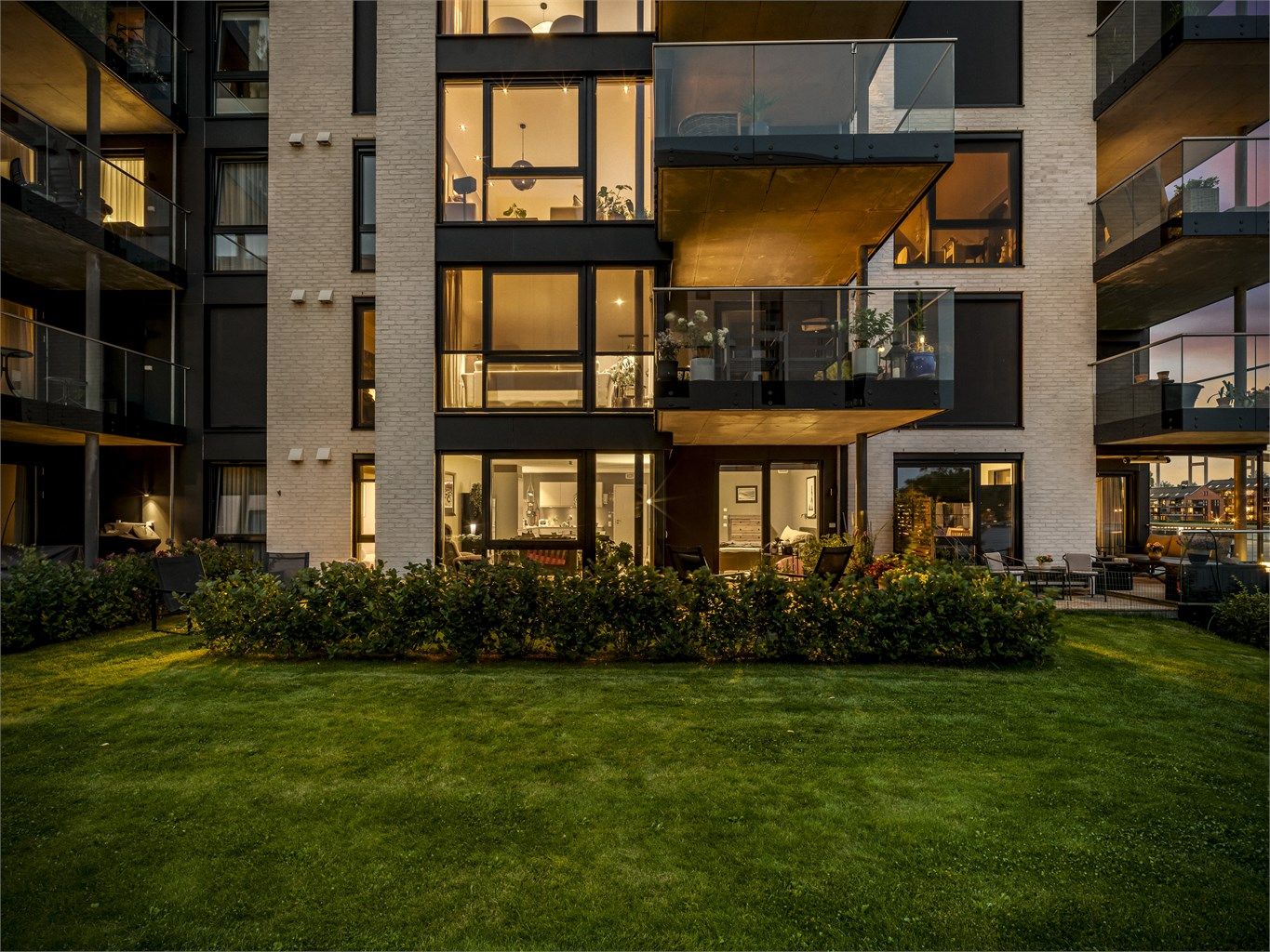 Parkmessig opparbeidede fellesarealer danner en velstelt ramme rundt sameiets leilighetsblokker.