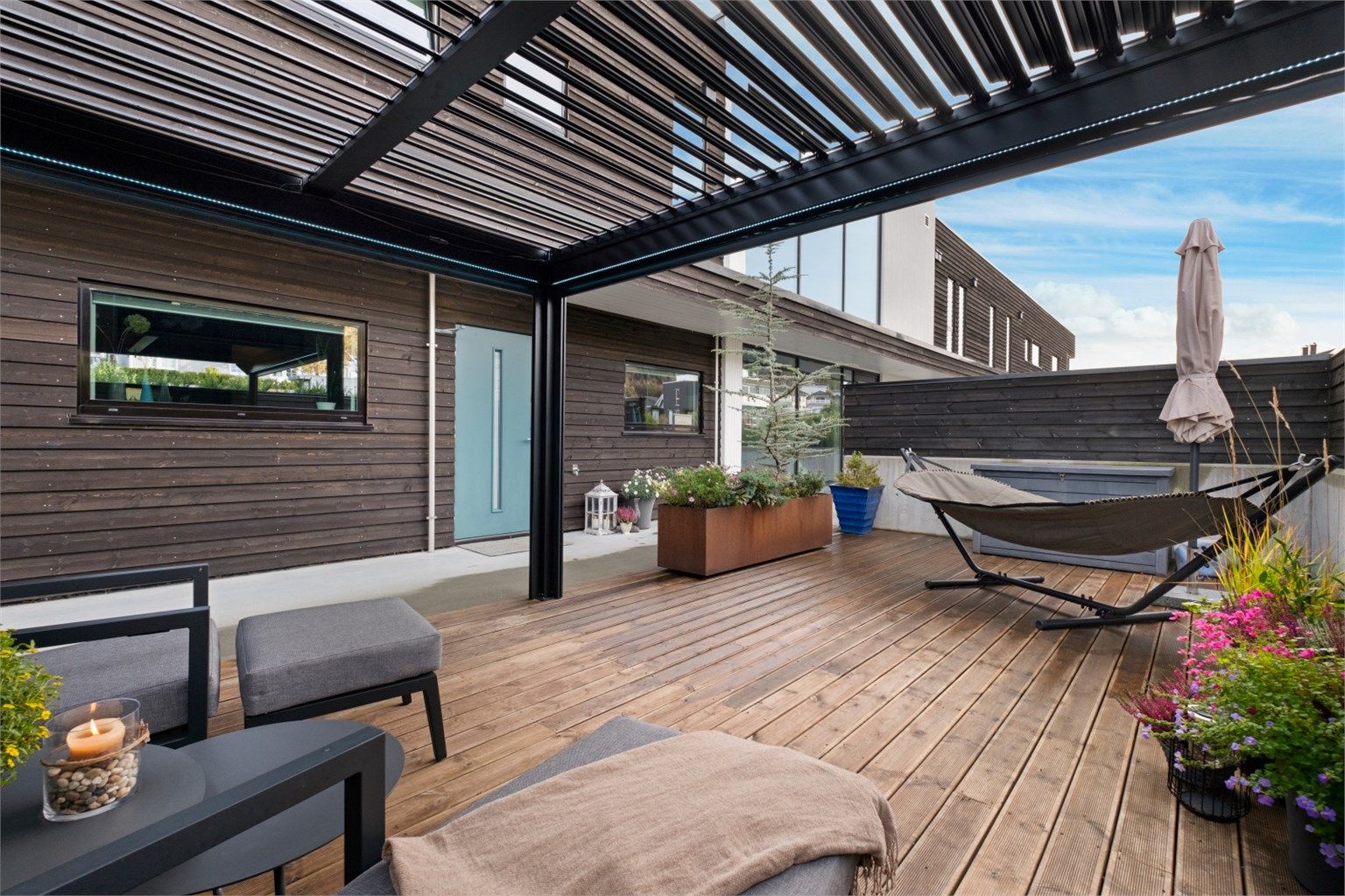 Flott uteplass med pergola skjermet med levegger av betong og tre 