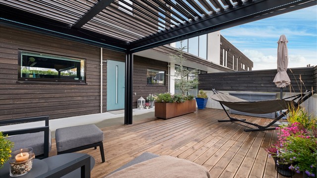 Flott uteplass med pergola skjermet med levegger av betong og tre