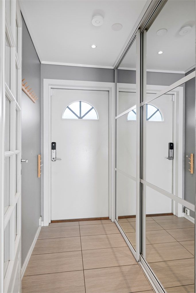 Entréen har flislagt gulv med varmekabler og en romslig skyvedørsgarderobe med speilfronter.