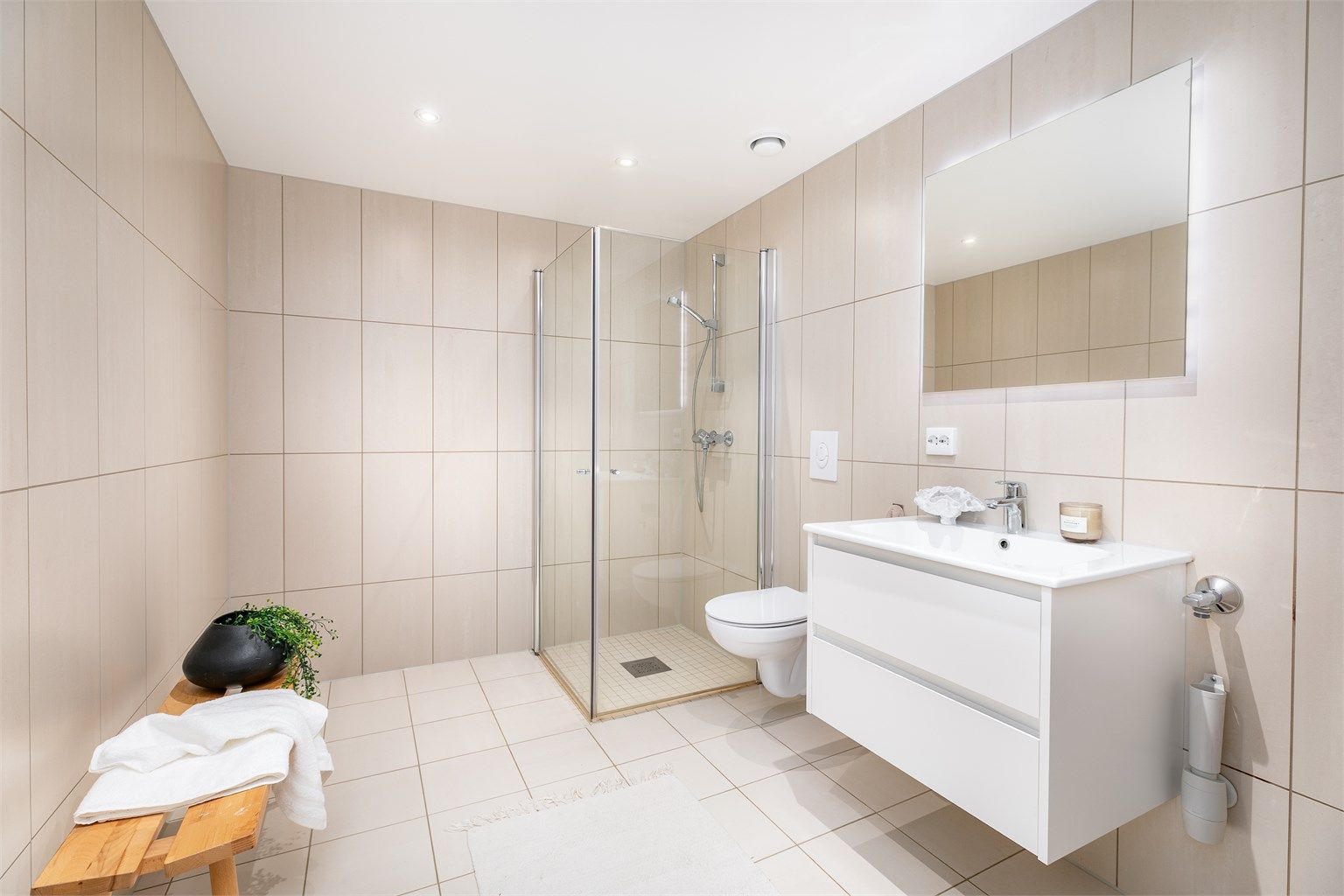 Badet er av generøs størrelse og utført med lyse fliser som skaper helhet.