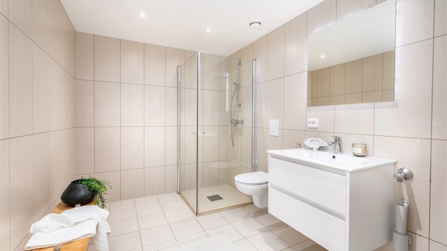 Badet er av generøs størrelse og utført med lyse fliser som skaper helhet.