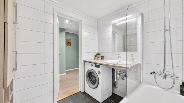 Baderomsinnredning med servant og veggskap gir praktisk oppbevaring.