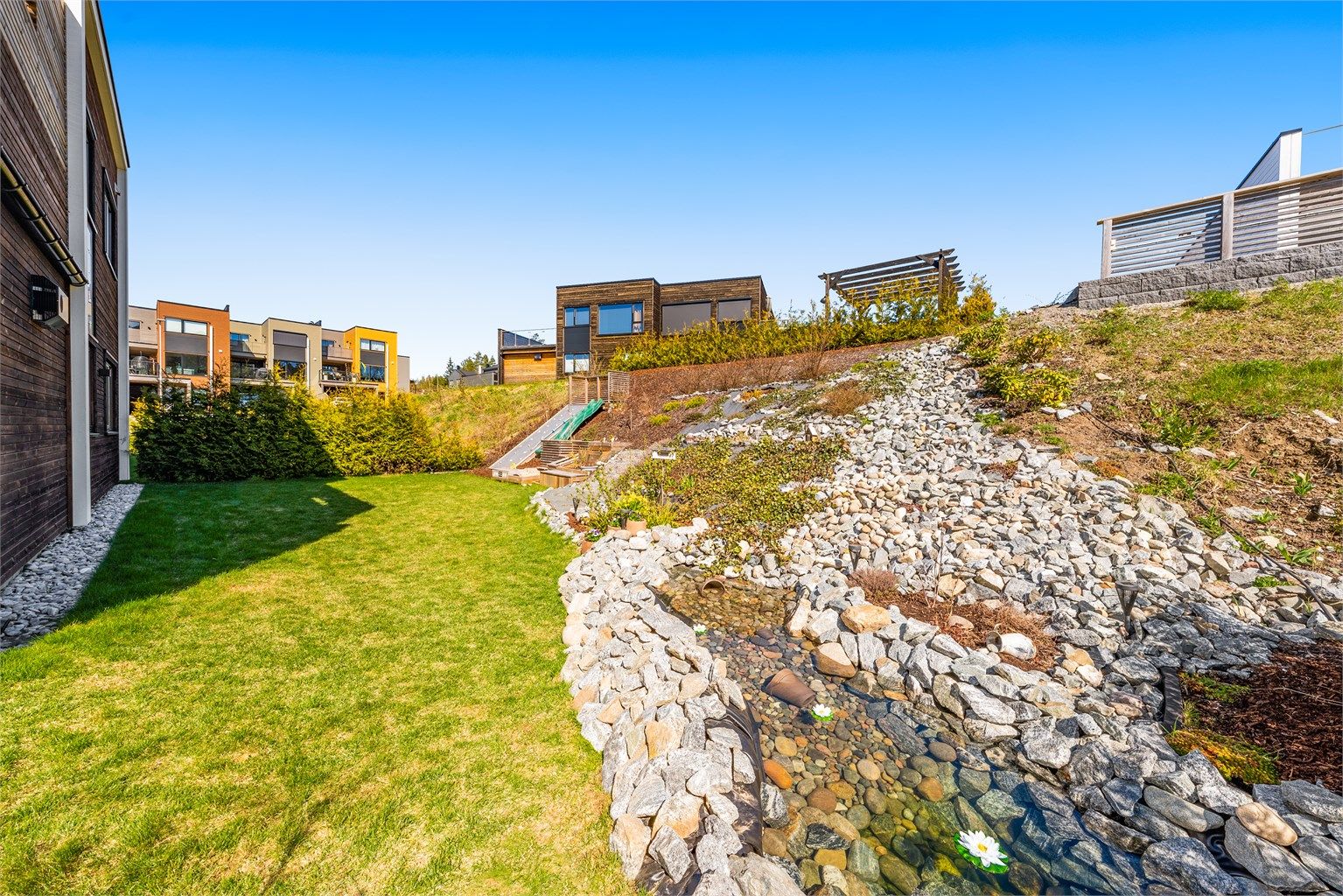 På baksiden av boligen kan de med grønne fingre holde det gående med diverse beplantning. Det er også innlagt dam i hagen. 