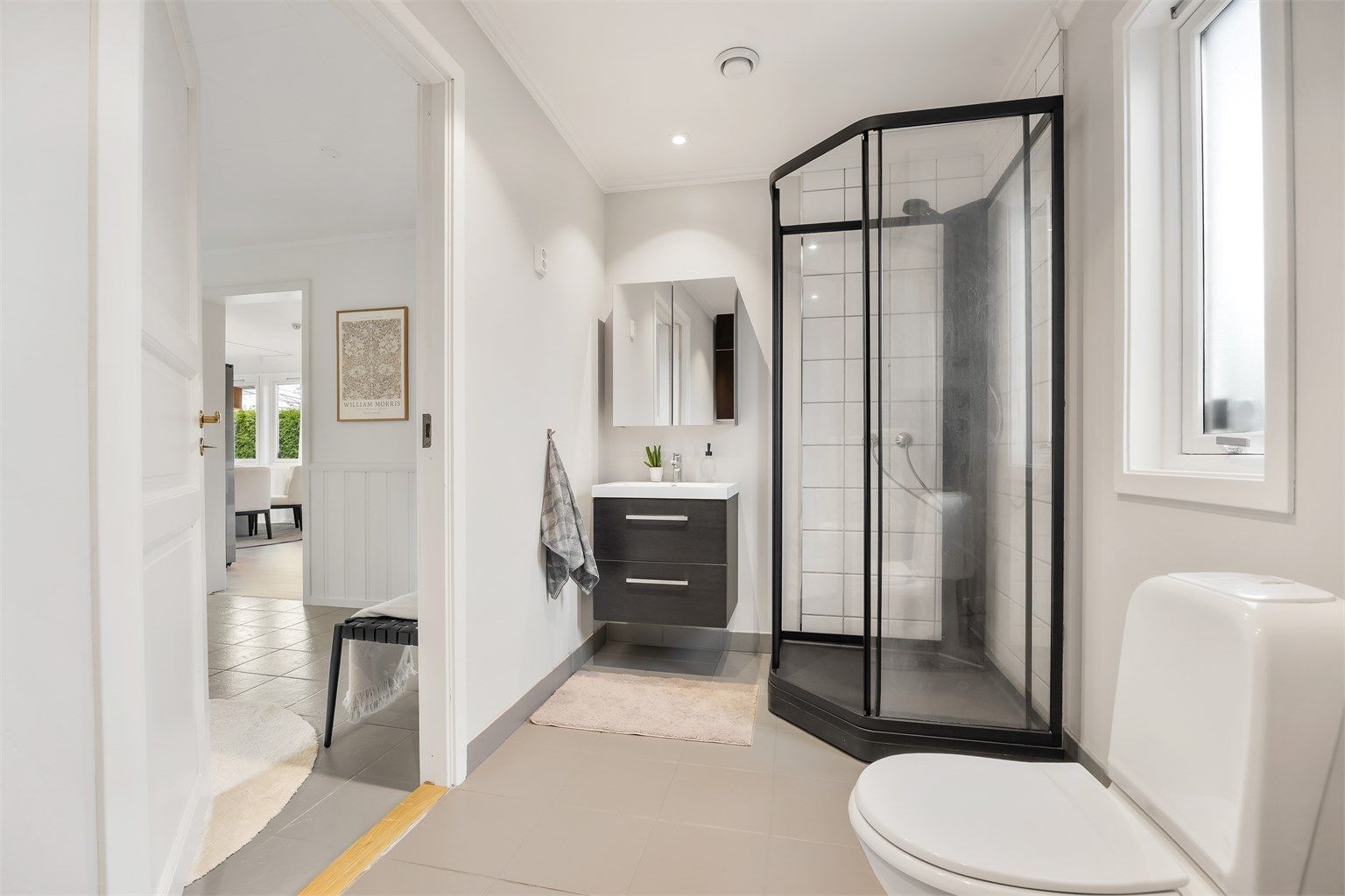 Badet i første etasje har flislagt gulv med gulvvarme, dusjkabinett og opplegg for vaskemaskin.