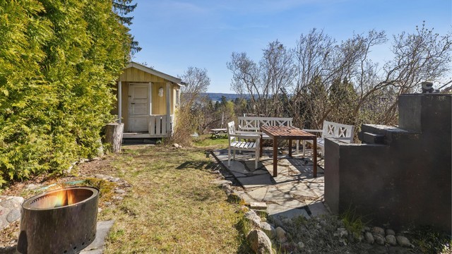 I hagen er det etablert en platting i skifer med utepeis, som skaper en svært hyggelig ramme for uteliv. Området har en idyllisk atmosfære, perfekt for sommerdager, barnelek og sosiale sammenkomster.