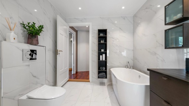 Badet er innredet med både badekar, dusjhjørne og vegghengt toalett.