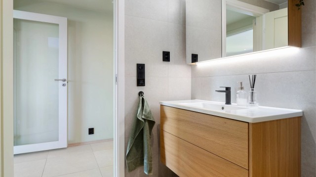 Badet har elektrisk gulvvarme, vegghengt toalett og speilskap med belysning.