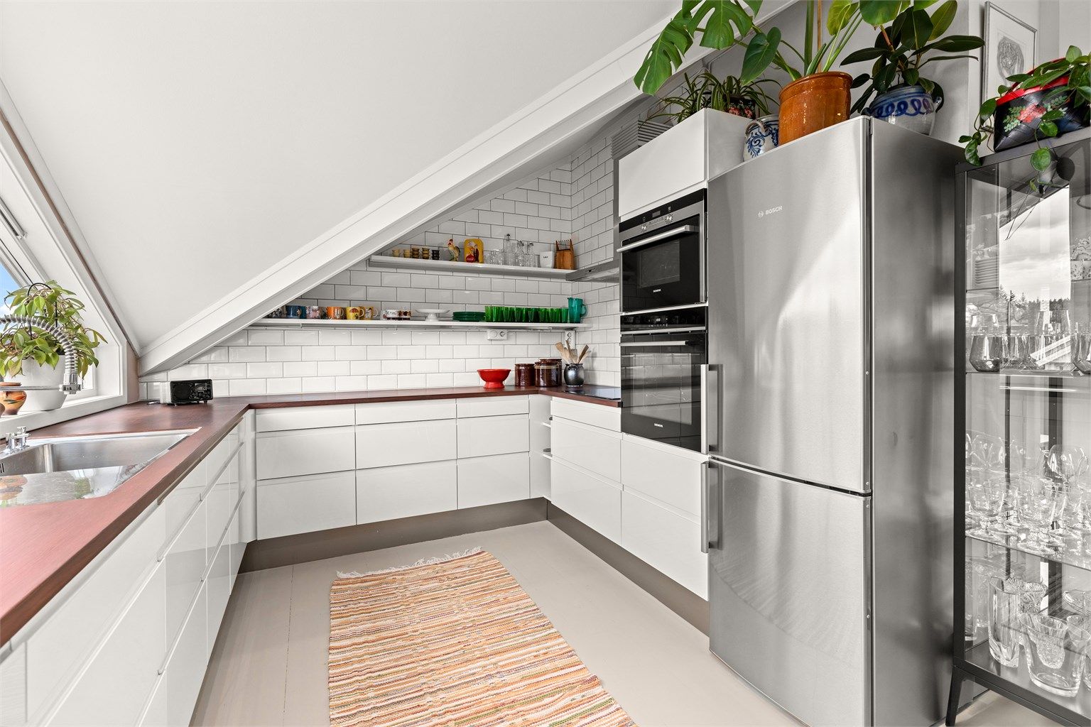 Kjøkkeninnredning fra HTH med slette fronter, benkeplater i heltre og integrert oppvaskmaskin, platetopp, komfyr og varmluftsovn. 