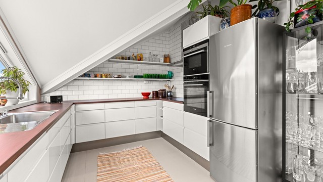 Kjøkkeninnredning fra HTH med slette fronter, benkeplater i heltre og integrert oppvaskmaskin, platetopp, komfyr og varmluftsovn.