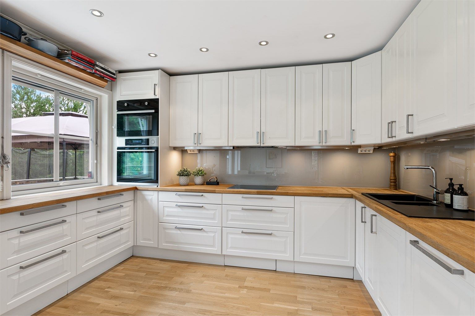 Innredningen er fra 2011, med hvite, profilerte fronter, vitrineskap og dobbel oppvaskkum nedfelt i en heltre benkeplate.