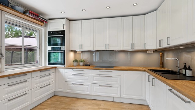 Innredningen er fra 2011, med hvite, profilerte fronter, vitrineskap og dobbel oppvaskkum nedfelt i en heltre benkeplate.