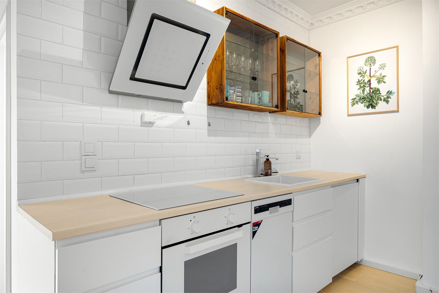 Videre er kjøkkenet utstyrt med integrert stekeovn, platetopp, oppvaskmaskin og kjøle-/fryseskap. Vegghengt kullfilterventilator over platetoppen.