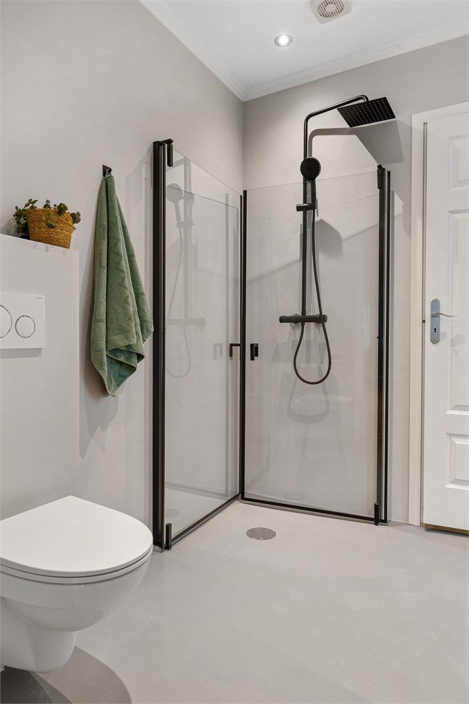 Lekker dusjsone med plassbesparende, glassvegger med sort innramming, som står godt i stil med dusjopplegget