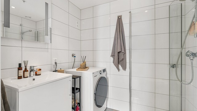 Flislagt bad fra 2021 med gulvvarme, dusjhjørne med glassdører og opplegg for vaskemaskin.