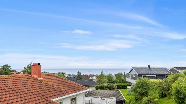 Fra verandaen er det flott utsikt over nærområdet og videre mot sjøen, en utsikt som også kan nytes fra kjøkkenet og stuen.